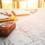 Contractor plans sitting on table with drafting tools